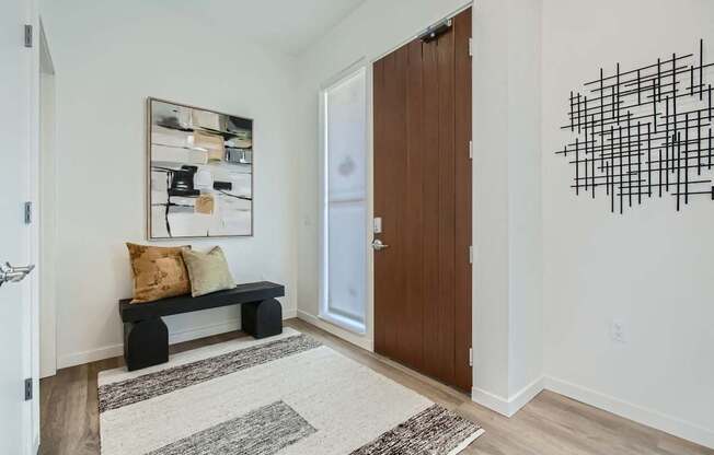 a hallway with a door to a room with a couch and a bench