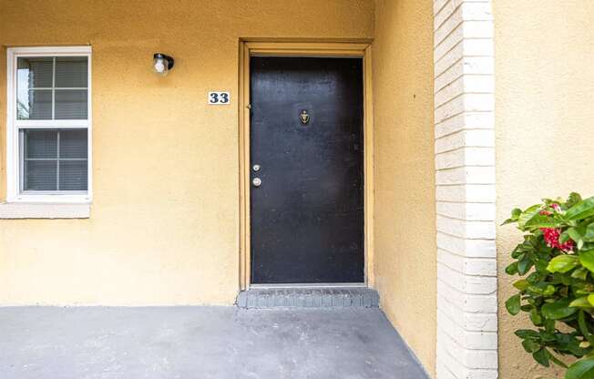 a yellow house with a black door and a porch