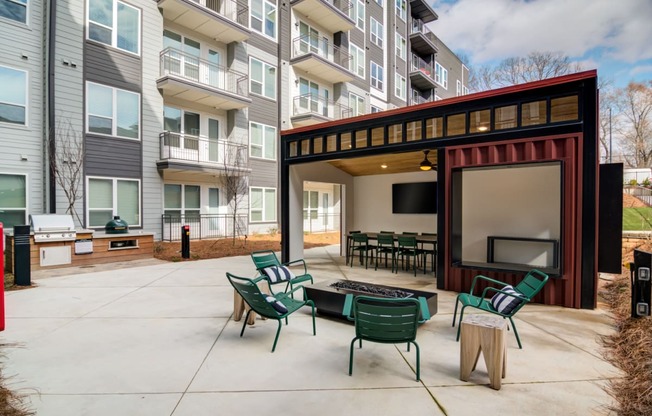 a patio with chairs and a fire pit in front of an apartment building