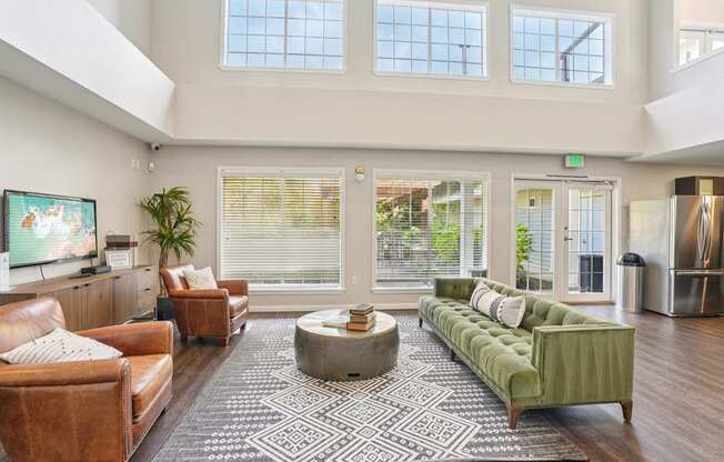 A sitting room with a brown leather couch, a green sofa, and a coffee table in the center.