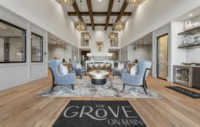 a living room with blue chairs and a rug that reads the grove on man