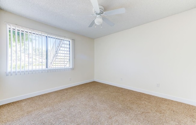 a bedroom with a ceiling fan and a window at Redlands Park Apts, Redlands, CA, 92373