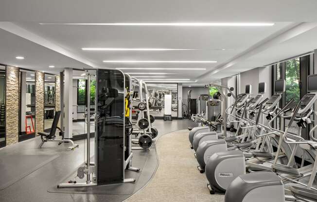 an image of a gym with cardio machines on the floor and a brick wall in the background