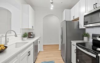 A kitchen with white cabinets and a blue rug on the floor.