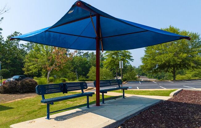 two benches with an umbrella on a sidewalk