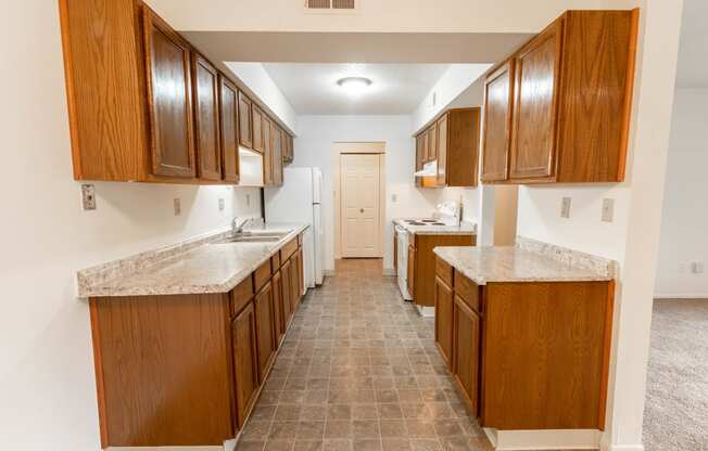 a kitchen with wooden cabinets and marble counter tops