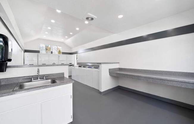 A modern kitchen with white cabinets and a grey floor.