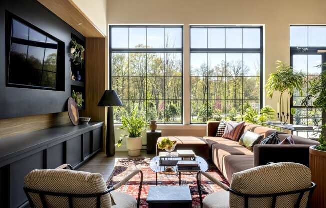 a living room with a couch and chairs and large windows