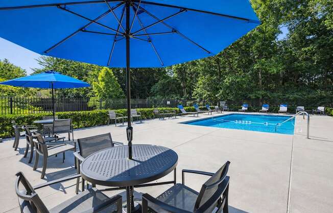 A blue umbrella is over a table with chairs around it.