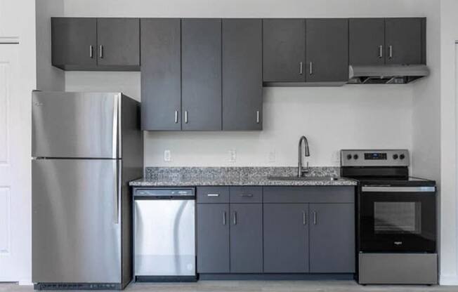 A modern kitchen with a stainless steel refrigerator, a dishwasher, a sink, and a stove.