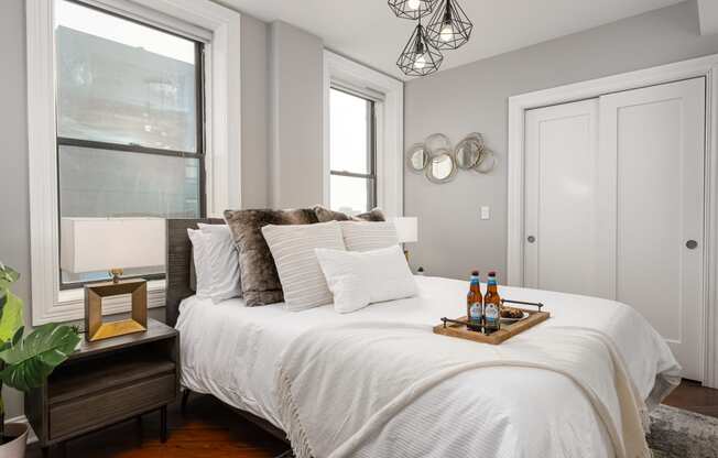 a bedroom with a white bed and two windows
