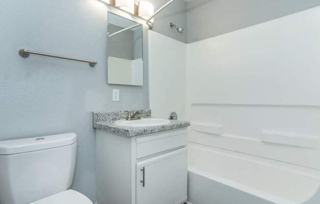 A white bathroom with a toilet, sink, and bathtub.