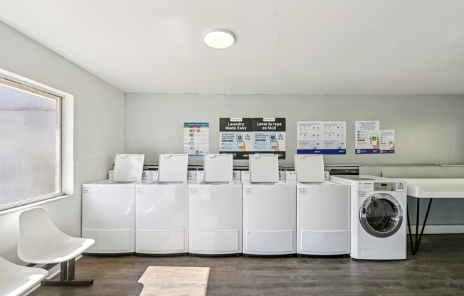 A row of white washing machines are lined up in a room.