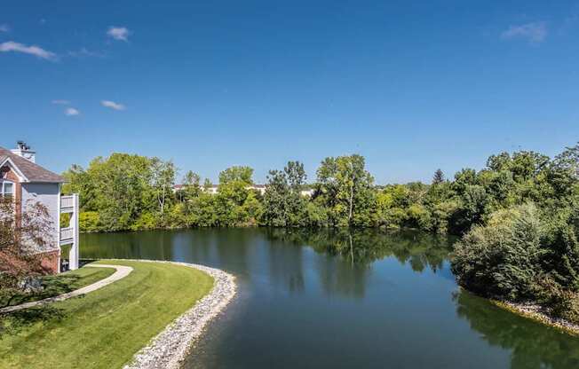 A serene landscape with a house, a lake, and a winding path.