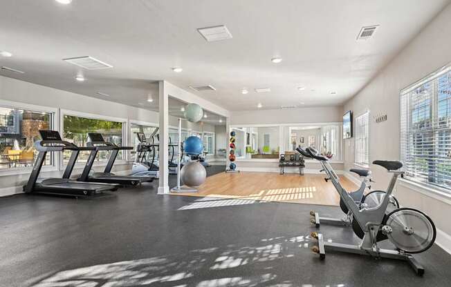 A spacious gym with a variety of equipment including a stationary bike, treadmill, and exercise ball.