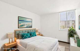 A bedroom with a bed, nightstand, and a painting on the wall.