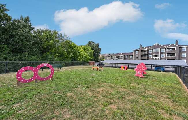 A grassy area with a pink sculpture and a building in the background.