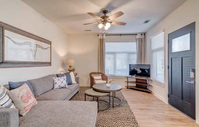 A living room with a grey couch, a coffee table, and a ceiling fan.