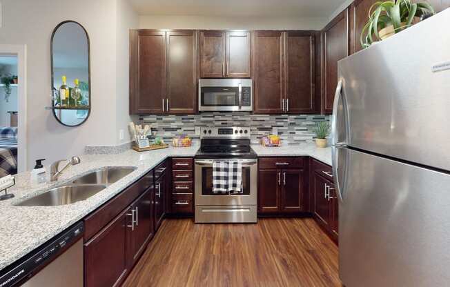a kitchen with dark wood cabinets and stainless steel appliances at The Bend Arbordale, Williamsburg