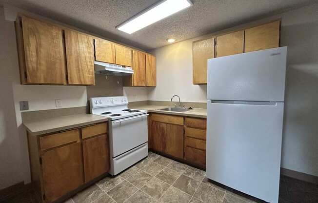 A kitchen with wooden cabinets and a white refrigerator.