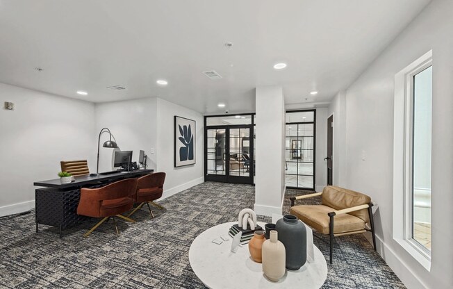 An office with desk, two chairs near a coffee table with another chair.