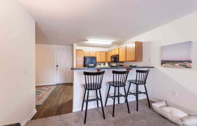 A kitchen area with a bar and chairs.