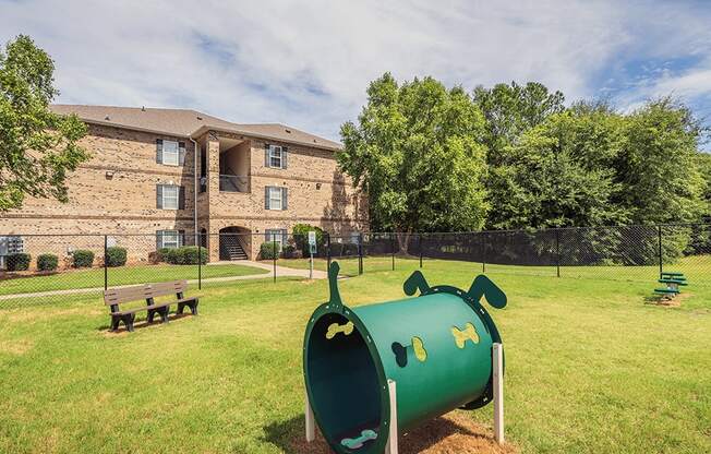 A playground with a green slide and a building in the background.