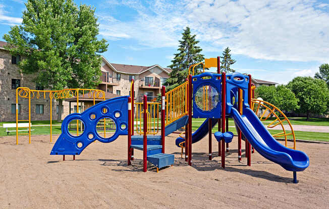 A playground with a blue slide and a yellow and blue climbing structure.