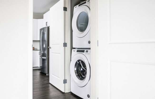 Compact stacked washer and dryer nestled in a hallway closet, providing convenient laundry facilities in a stylish apartment.