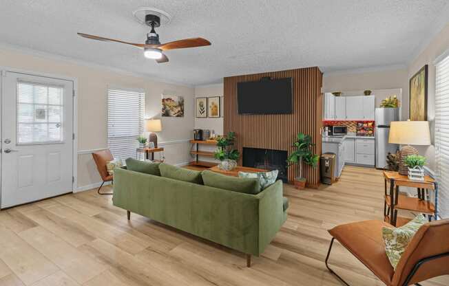 a living room with a green couch and a ceiling fan
