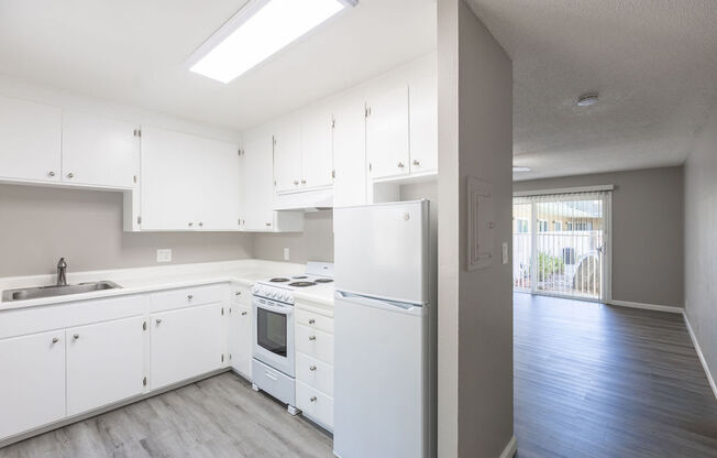 an empty kitchen with white cabinets and a window