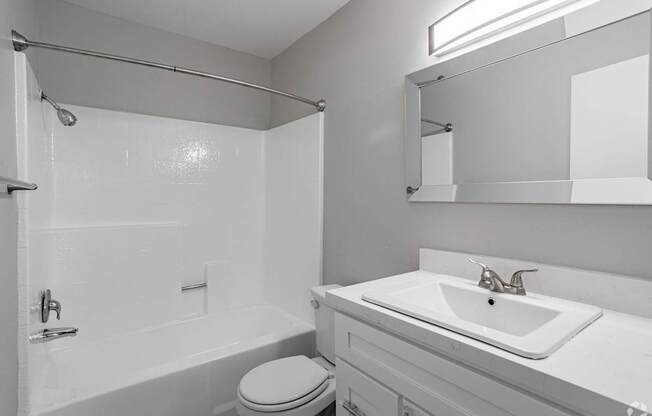 A white bathroom with a toilet, sink, and shower.