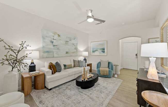 A living room with a white couch, a rug, and a painting on the wall.
