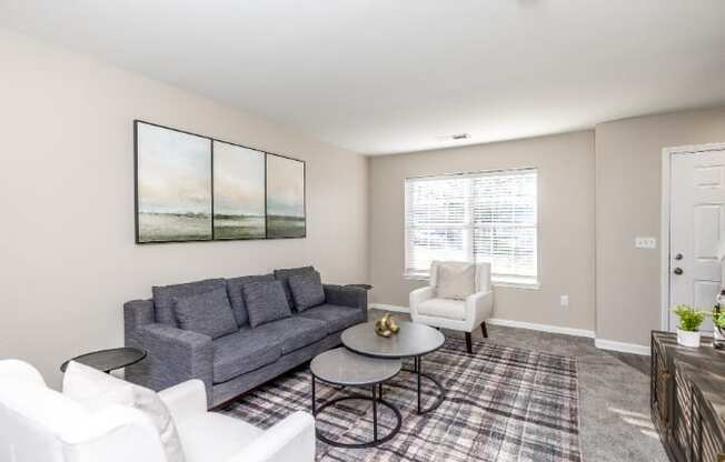 A living room with a grey couch, a coffee table, and a painting on the wall.