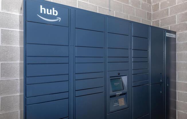 A row of Amazon lockers are lined up against a brick wall.