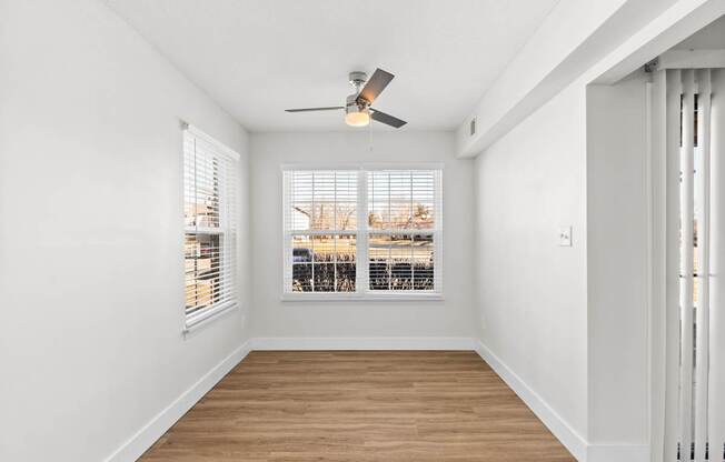 A room with a ceiling fan and a window overlooking a cityscape.