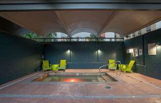 A hot tub is surrounded by four chairs in a room with a black wall.