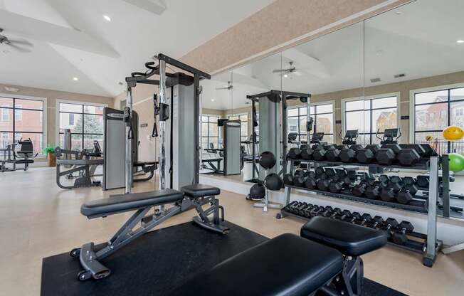 A gym with a variety of equipment including weights and a bench.