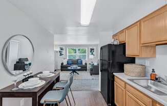 a kitchen and living room with a black refrigerator and a table with chairs