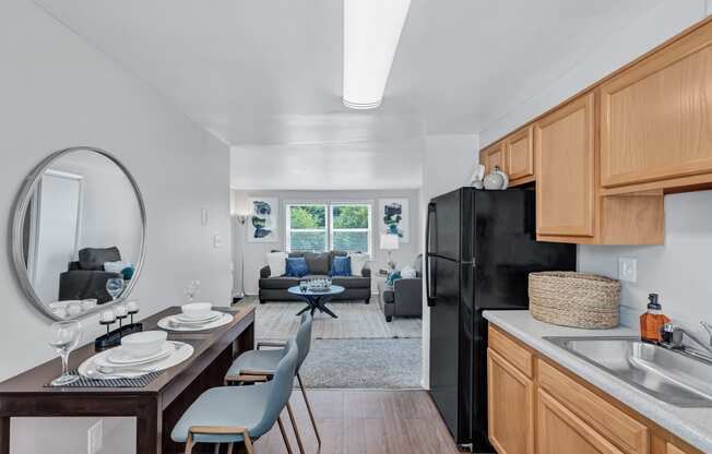 a kitchen and living room with a black refrigerator and a table with chairs
