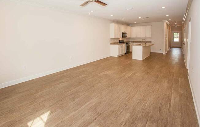 an empty living room and kitchen with a ceiling fan