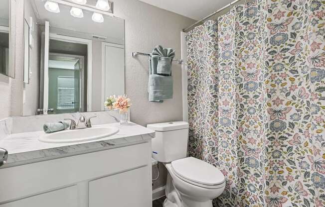 A white bathroom with a floral shower curtain.