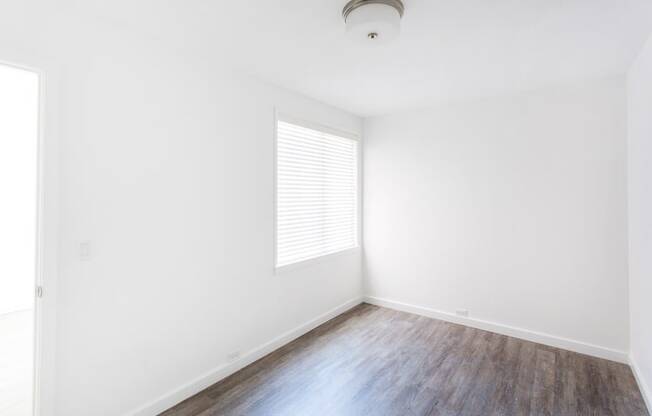 a bedroom with white walls and hardwood floors