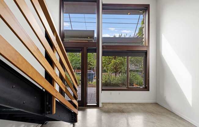A room with a wooden staircase and a glass door leading to a balcony.