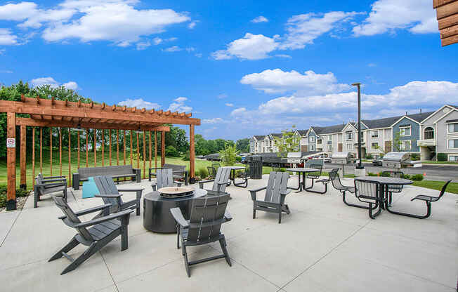 an outdoor pergola with tables and fire pit with seating at The Crossings Apartments, Michigan, 49508