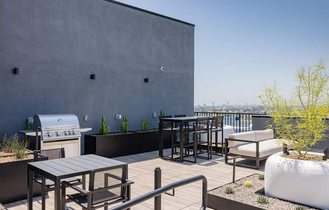 A patio with a table, chairs, and a grill at Skylar At Sunset Apartments, Los Angeles