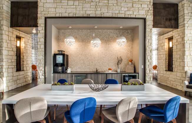 a large table with blue chairs and a kitchen in the background