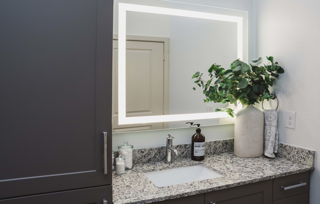 Designer bathrooms with granite countertops and backlit mirrors