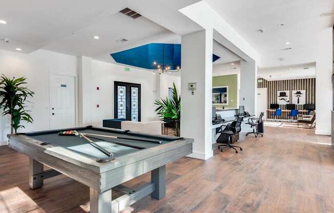 A pool table is in the middle of a room with a wooden floor.
