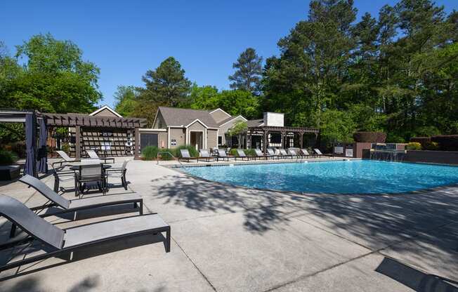 Wynnwood Vinings resident pool with lounge chairs and view of outdoor TV lounge with couches